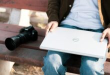 Kamera ve Laptop ile bir bankta oturan insan