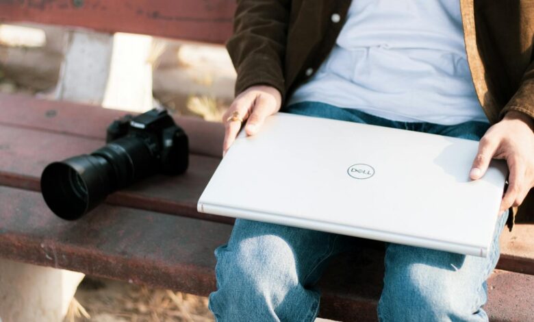 Kamera ve Laptop ile bir bankta oturan insan